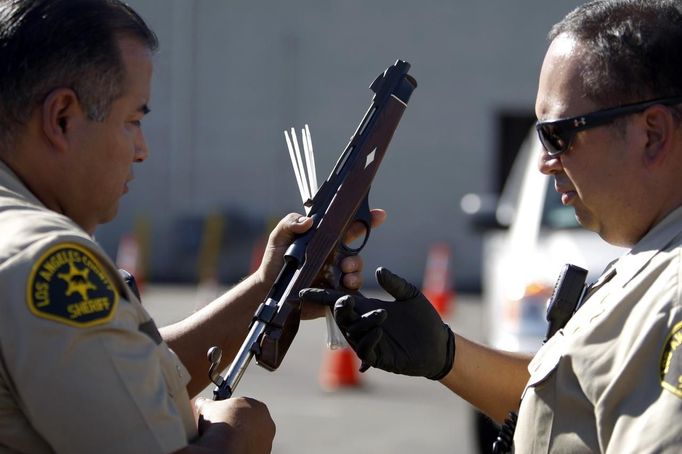 Los Angeles County Sheriff deputies take in guns from motorists trading them in at the 'Gifts for Guns' gun buyback in Compton, California, January 21, 2013. People can trade in their guns anonymously and with no questions asked in exchange for $200 gift cards for assault weapons, $100 gift cards for shotguns, handguns and rifles, and $50 for non-operational firearms. U.S. President Barack Obama is pushing to address controversial issues surrounding gun violence and regulation as he begins his second term in office. REUTERS/David McNew (UNITED STATES - Tags: POLITICS SOCIETY TPX IMAGES OF THE DAY) Published: Led. 21, 2013, 10:58 odp.