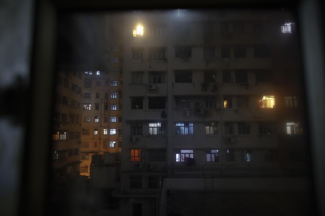 An apartment block is seen through the window of a space where people live in wooden boxes in Hong Kong October 9, 2012. In Hong Kong's middle-class residential area, short distance from its shopping and financial districts, 24 people live in these wooden boxes, or "coffin homes", packed in a single apartment of little over 50 square meters. Its residents pay 1450 Hong Kong dollars ($180) for their living space built of wooden panels of 2 meters by 70 cm. To maximize income from the rent in central Hong Kong landlords build "coffin homes", nicknamed due to their resemblance to real coffins. Space has always been at a premium in Hong Kong where developers plant high-rises on every available inch. REUTERS/Damir Sagolj (CHINA - Tags: SOCIETY REAL ESTATE BUSINESS) Published: Říj. 9, 2012, 1:55 odp.