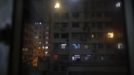 An apartment block is seen through the window of a space where people live in wooden boxes in Hong Kong October 9, 2012. In Hong Kong's middle-class residential area, short distance from its shopping and financial districts, 24 people live in these wooden boxes, or "coffin homes", packed in a single apartment of little over 50 square meters. Its residents pay 1450 Hong Kong dollars ($180) for their living space built of wooden panels of 2 meters by 70 cm. To maximize income from the rent in central Hong Kong landlords build "coffin homes", nicknamed due to their resemblance to real coffins. Space has always been at a premium in Hong Kong where developers plant high-rises on every available inch. REUTERS/Damir Sagolj (CHINA - Tags: SOCIETY REAL ESTATE BUSINESS) Published: Říj. 9, 2012, 1:55 odp.