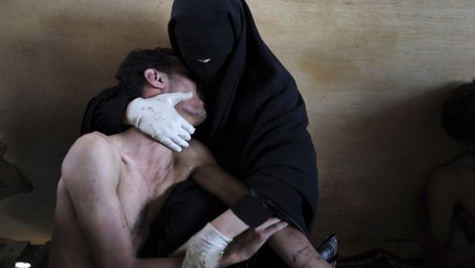 Na vítězné fotografii zahalená žena drží v náručí zraněného příbuzného před provizorní nemocnicí zřízenou v jemenském hlavním městě Saná.