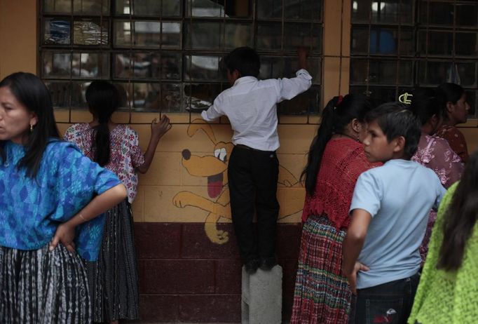 A child looks at a crime scene in a classroom of a primary school after two children, a 8-year-old and a 13-year-old, were killed by a man with a machete in Tactic, in Alta Verapaz region, some 189km (117 miles) from Guatemala City, September 12, 2012. The man was then lynched and burnt alive by a mob at the school. REUTERS/Jorge Dan Lopez (GUATEMALA - Tags: EDUCATION CRIME LAW) Published: Zář. 13, 2012, 1:44 dop.