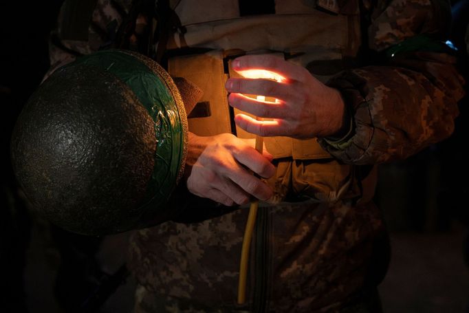 A Ukrainian soldier of the 14th separate mechanized brigade holds a candle during a Christmas Eve service near the front line outside Kupiansk as Ukrainians celebrate the