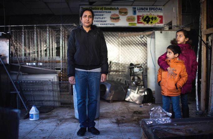 Jaswinder Kaur poses for a photograph with her two children Taranjot, 9, and Harshjot, 5, as they stand in the remains of their convenience and deli store which was destroyed by Hurricane Sandy in New Dorp Beach, Staten Island November 14, 2012. Jaswinder, a single mother, faces an uncertain furture as the building that she rented may need to be torn down. At least 23 New Yorkers were killed in this low lying area of the south shore of Staten Island where mostly one-story former beach bungalows were inundated by flooding. Picture taken November 14, 2012. REUTERS/Mike Segar (UNITED STATES - Tags: DISASTER ENVIRONMENT) ATTENTION EDITORS PICTURE 02 OF 19 FOR PACKAGE 'SURVIVING SANDY' SEARCH 'SEGAR SANDY' FOR ALL PICTURES Published: Lis. 20, 2012, 3:30 odp.