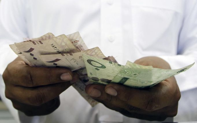 A Saudi jeweller counts Saudi Riyal banknotes money after selling gold to a customer in a jewellery shop at the surrounding area of the Grand Mosque during the annual haj pilgrimage in the holy city of Mecca October 20, 2012. They might wear the humble white sheets required for Islam's haj pilgrimage, but for many visitors thronging Mecca's streets, the perfect souvenir of their trip is that most glittering of commodities: gold. For most pilgrims haj represents the fulfilment of a lifelong ambition and many of them want to commemorate their journey with keepsakes or gifts for relatives that carry a special religious significance. Picture taken October 20, 2012. REUTERS/Amr Abdallah Dalsh (SAUDI ARABIA - Tags: RELIGION BUSINESS) Published: Říj. 23, 2012, 11:04 odp.