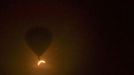 In this photo provided by Tourism Queensland, a hot air balloon floats in the air as a solar eclipse is observed near Cairns, in Queensland state, Australia, Wednesday, Nov. 14, 2012. Starting just after dawn, the eclipse cast its 150-kilometer (95-mile) shadow in Australia's Northern Territory, crossed the northeast tip of the country and was swooping east across the South Pacific, where no islands are in its direct path. (AP Photo/Tourism Queensland, David Barker) EDITORIAL USE ONLY