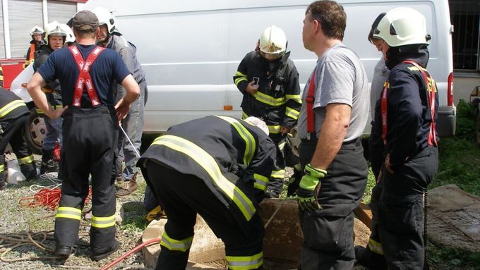 Jeden z hasičů se pomocí lezeckého vybavení spustil do studny, upevnil jednu dívku do trojcípého šátku a další hasiči ji vytáhli ven.