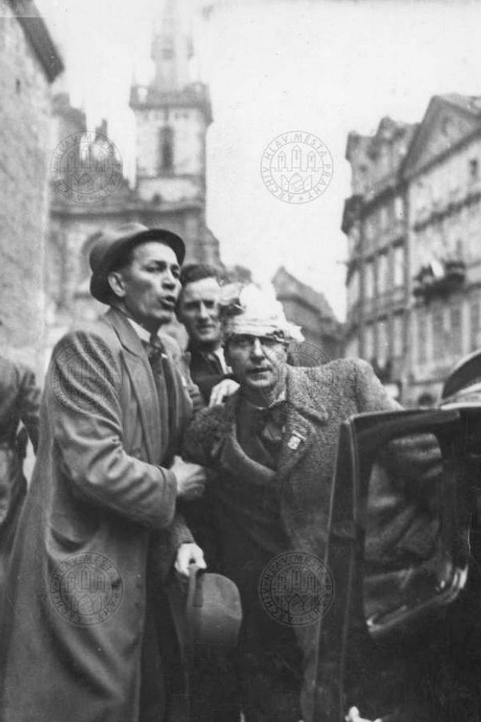 Lidé pomáhají nastoupit do automobilu zraněnému muži v Železné ulici během pražského povstání v květnu 1945.