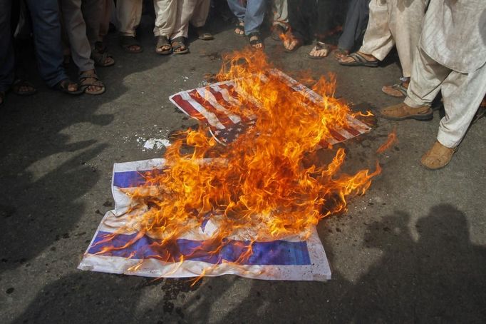 Supporters from the Jamaat Ahle Sunnat Pakistan religious political party burn U.S and Israel flags during an anti-American protest in Karachi September 19, 2012. Some 700 protesters gathered in a demonstration to condemn a film produced in the U.S. mocking the Prophet Mohammad. REUTERS/Athar Hussain (PAKISTAN - Tags: POLITICS CIVIL UNREST RELIGION) Published: Zář. 19, 2012, 3:39 odp.