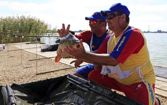 Valeriu Martoiu (L) and Ionel Ghelase (R) of Romania pose with a carp they caught during the 14th Carpfishing World Championship in Corbu village, 310 km (192 miles) east of Bucharest, September 29, 2012. REUTERS/Radu Sigheti (ROMANIA - Tags: SOCIETY) Published: Zář. 29, 2012, 4:30 odp.