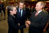 Ze zákulisí zahajovacího ceremoniálu: Louis Sarkozy (vlevo) se zdraví s ruským premiérem Vladimírem Putinem, přihlíží otec Nicolas Sarkozy, prezident Francie.