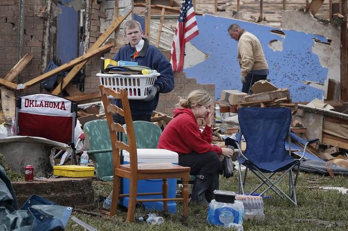 Resident Taylor Tennyson sits in the front yard as family members salvage the remains from their home which was left devastated by a tornado in Moore, Oklahoma, in the outskirts of Oklahoma City May 21, 2013. Rescuers went building to building in search of victims and thousands of survivors were homeless on Tuesday, a day after a massive tornado tore through a suburb of Oklahoma City, wiping out whole blocks of homes and killing at least 24 people. REUTERS/Adrees Latif (UNITED STATES - Tags: DISASTER ENVIRONMENT TPX IMAGES OF THE DAY) Published: Kvě. 21, 2013, 9:33 odp.