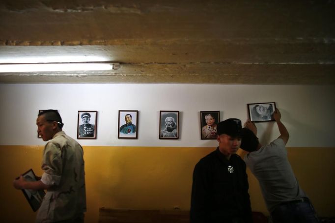 Members of the Mongolian neo-Nazi group Tsagaan Khass hang up portraits of Mongolian heroes at the group's headquarters in Ulan Bator June 24, 2013. The group has rebranded itself as an environmentalist organisation fighting pollution by foreign-owned mines, seeking legitimacy as it sends Swastika-wearing members to check mining permits. Over the past years, ultra-nationalist groups have expanded in the country and among those garnering attention is Tsagaan Khass, which has recently shifted its focus from activities such as attacks on women it accuses of consorting with foreign men to environmental issues, with the stated goal of protecting Mongolia from foreign mining interests. This ultra-nationalist group was founded in the 1990s and currently has 100-plus members. Picture taken June 24, 2013. REUTERS/Carlos Barria (MONGOLIA - Tags: POLITICS ENVIRONMENT BUSINESS SOCIETY EMPLOYMENT) ATTENTION EDITORS: PICTURE 17 OF 25 FOR PACKAGE 'MONGOLIA'S ENVIRONMENTAL NEO-NAZIS'. TO FIND ALL IMAGES SEARCH 'TSAGAAN KHASS' Published: Čec. 2, 2013, 9:58 dop.