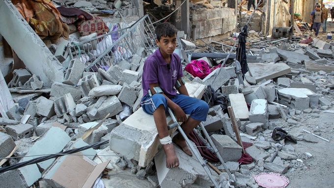 Zraněný Palestinec sedí po izraelském náletu v troskách zničeného obydlí.
