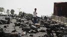 A boy stands on a street littered with cooking gas cylinders after a fire and explosions destroyed a nearby gas storage during clashes between fighters of the Popular Res