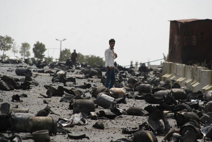 A boy stands on a street littered with cooking gas cylinders after a fire and explosions destroyed a nearby gas storage during clashes between fighters of the Popular Res