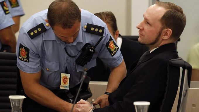 Policista odemyká Breivikovi pouta při zahájení soudního procesu.