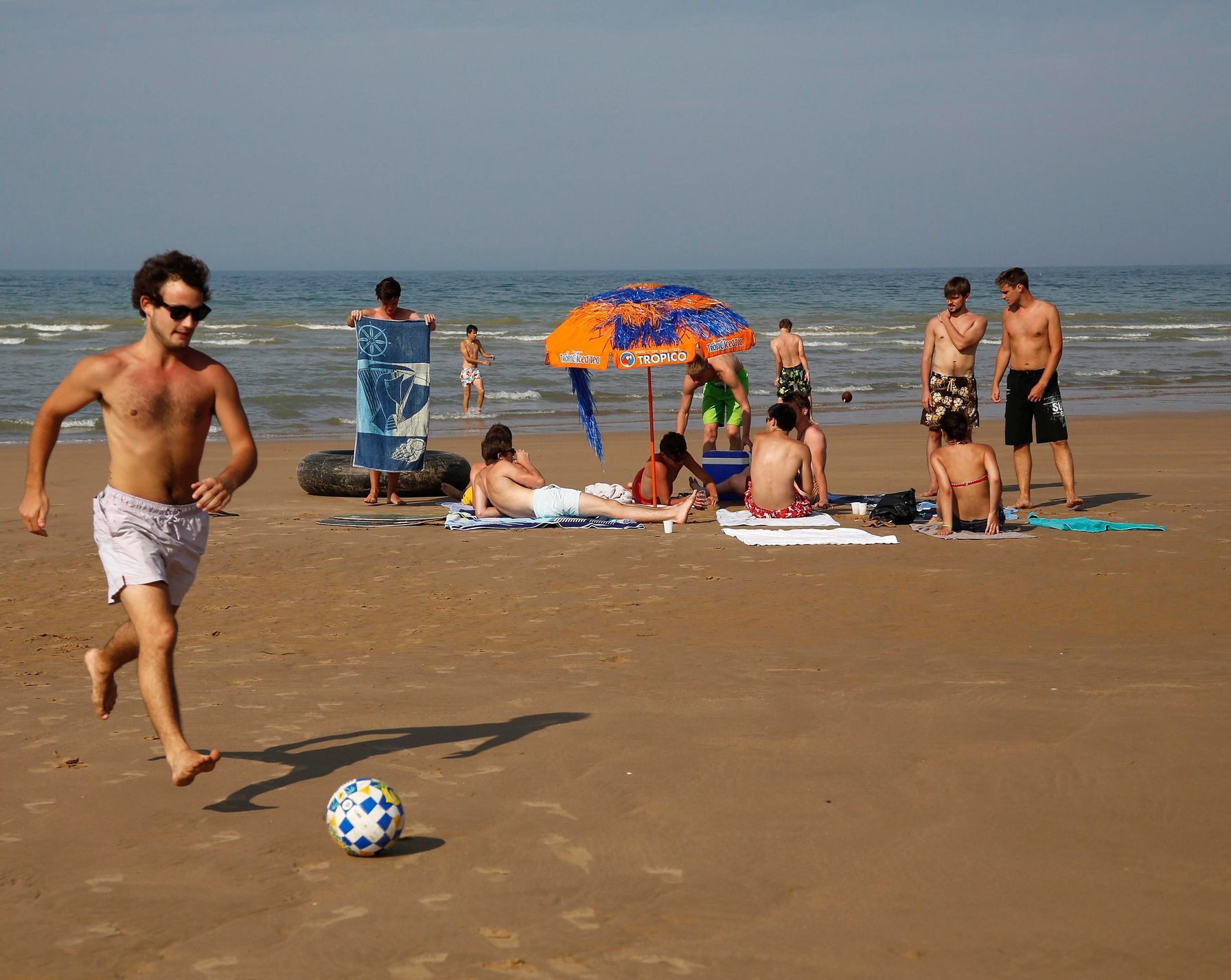 Youths enjoy the sunshine on the former D-Day landing zone of Omaha beach near Vierville sur Mer