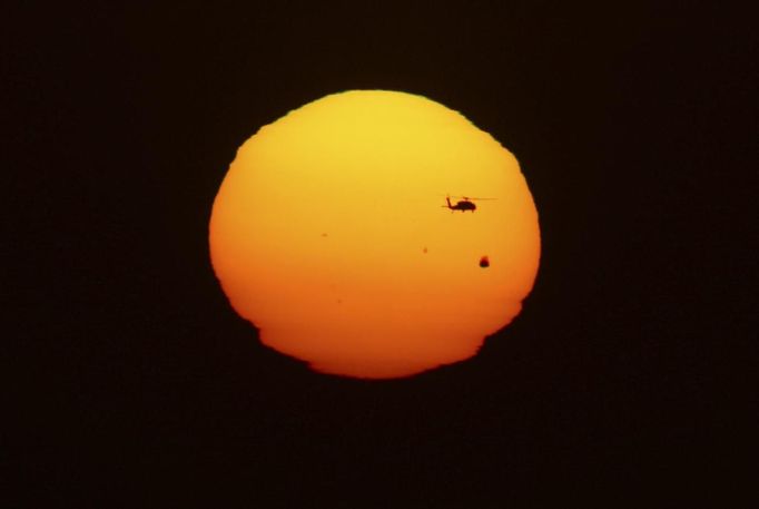 A helicopter flies past as the planet Venus makes its transit across the sun over Tijuana, June 5, 2012. Venus made a slow transit across the face of the sun on Tuesday, the last such passing that will be visible from Earth for 105 years. REUTERS/Jorge Duenes (MEXICO - Tags: ENVIRONMENT SCIENCE TECHNOLOGY TPX IMAGES OF THE DAY) Published: Čer. 6, 2012, 6:23 dop.