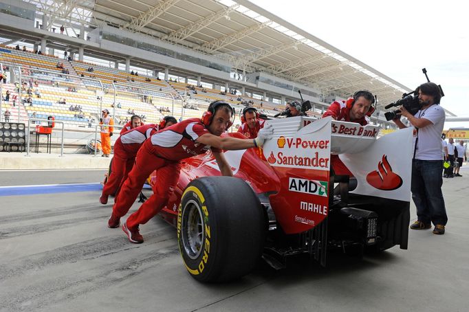 Mechanici tlačí monopost Ferrari do boxů. V závodě byly oba vozy dokonale spolehlivé.