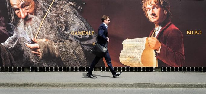 A man walks along a fence hung with large format hoardings of J. R. R. Tolkien characters from The Hobbit movie in Wellington November 27, 2012. New Zealand's capital city was rushing to complete its transformation into a haven for hairy feet and pointed ears on Tuesday as stars jetted in for the long-awaited world premiere of the first movie of the Hobbit trilogy. REUTERS/Mark Coote (NEW ZEALAND - Tags: ENTERTAINMENT) Published: Lis. 27, 2012, 3:04 dop.