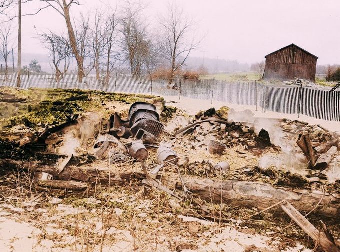 Pohled na doutnající trosky domu Eda Geina v Plainfieldu, Wisconsin, po požáru dne 20. března 1958. Kolorováno