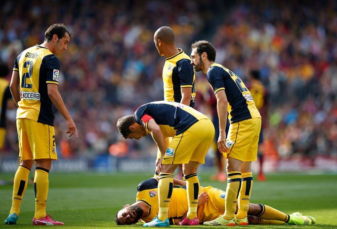 Atletico Madrid's Arda Turan lies on the pitch during their soccer match against Barcelona in Barcelona