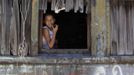 Ruth eats a fruit while sitting in a window of a train carriage she calls home in Cadereyta on the outskirts of Monterrey August 7, 2012. Ruth, her eight other family members and their pets have been living in the abandoned carriage next to a train track for the last 15 years. Ruth's grandparents moved from Tamaulipas to Cadereyta after one of their sons was killed on the street by a stray bullet. The family moved into the carriage, which was empty after having been occupied by a vagabond, after living for the first five years in a rented room after arriving in Cadereyta. Picture taken August 7, 2012. REUTERS/Daniel Becerril (MEXICO - Tags: SOCIETY) Published: Srp. 11, 2012, 2:23 dop.