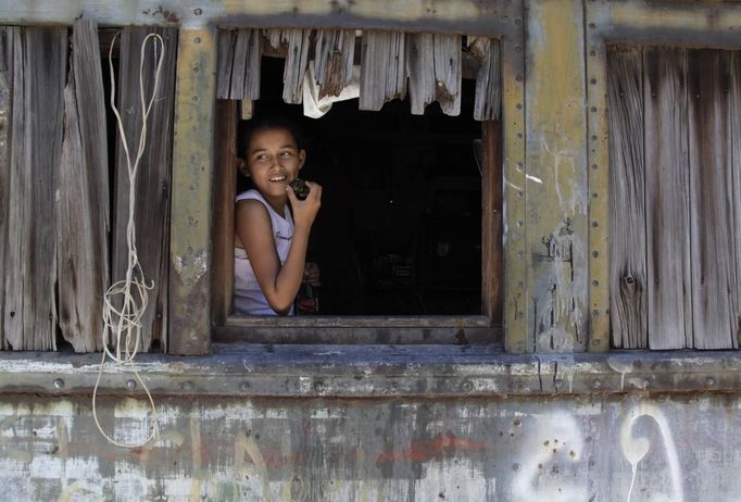 Ruth eats a fruit while sitting in a window of a train carriage she calls home in Cadereyta on the outskirts of Monterrey August 7, 2012. Ruth, her eight other family members and their pets have been living in the abandoned carriage next to a train track for the last 15 years. Ruth's grandparents moved from Tamaulipas to Cadereyta after one of their sons was killed on the street by a stray bullet. The family moved into the carriage, which was empty after having been occupied by a vagabond, after living for the first five years in a rented room after arriving in Cadereyta. Picture taken August 7, 2012. REUTERS/Daniel Becerril (MEXICO - Tags: SOCIETY) Published: Srp. 11, 2012, 2:23 dop.