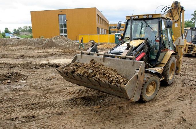 Ve druhé části parcely už bagry hloubí základy. Starší budovy školy jsou hned vedle.