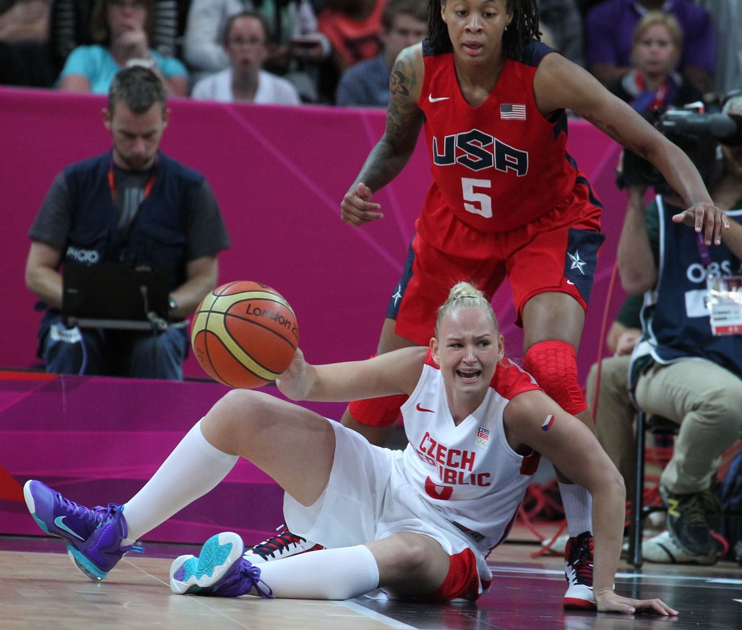 Česká basketbalistka Michaela Zrůstová se rozčiluje po pádu pod Američankou Simeone Augustusovou v utkání skupiny A na OH 2012 v Londýně