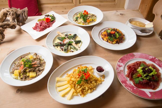 Typické engadinské pokrmy - Pizzoccheri, Salsiz, Maluns, Capuns, Pizokel, Plain in Pigna a sušené masi Bündnerfleisch (zleva doprava)