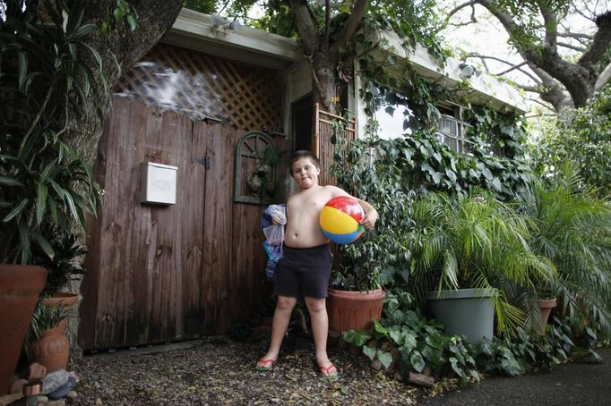 Davidson Aero Smith, 7, stands outside the trailer in which his family has lived for eight years, in Village Trailer Park in Santa Monica, California, July 13, 2012. Developer Marc Luzzatto wants to relocate residents from the trailer park to make way for nearly 500 residences, office space, stores, cafes and yoga studios, close to where a light rail line is being built to connect downtown Los Angeles to the ocean. Village Trailer Park was built in 1951, and 90 percent of its residents are elderly, disabled or both, according to the Legal Aid Society. Many have lived there for decades in old trailers which they bought. The property is valued at as much as $30 million, according the LA Times. REUTERS/Lucy Nicholson (UNITED STATES - Tags: REAL ESTATE BUSINESS POLITICS SOCIETY) Published: Čec. 14, 2012, 7:44 dop.