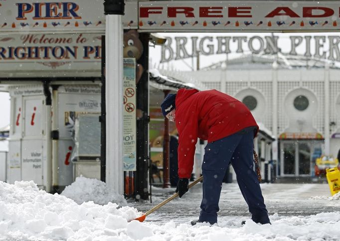 A worker clears snow from the area in front of Brighton Pier in Brighton, southern England March 12, 2013. Southern England was hit with heavy snow overnight. REUTERS/Luke MacGregor (BRITAIN - Tags: ENVIRONMENT SOCIETY) Published: Bře. 12, 2013, 1:16 odp.