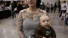 A tattooed participant in the Hampton Roads Tattoo Festival holds her baby in Virginia March 3, 2012. The hobby of collecting tattoos has exploded into the mainstream of society with tattoo conventions and festivals held year-round across the United States and the world. Picture taken March 3, 2012. REUTERS/Larry Downing (UNITED STATES - Tags: SOCIETY) ATTENTION EDITORS PICTURE 05 OF 31 FOR PACKAGE 'ADDICTED TO THE NEEDLE' TO FIND ALL PICTURES SEARCH 'ADDICTED NEEDLE' Published: Čer. 29, 2012, 12:58 odp.