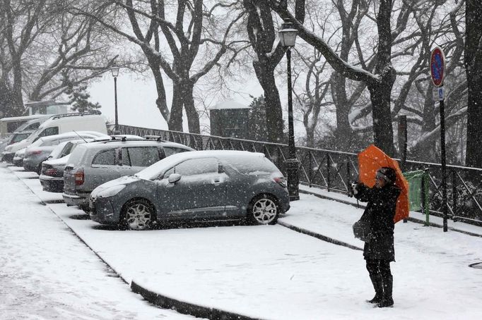 A woman takes a picture as she walks on a snow-covered street at the Butte Montmartre area in Paris March 12, 2013 as winter weather with snow and freezing temperatures returns to northern France. REUTERS/Jacky Naegelen (FRANCE - Tags: ENVIRONMENT) Published: Bře. 12, 2013, 11:59 dop.