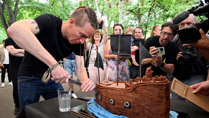 Předseda Pirátů Ivan Bartoš krájí dort na oslavě 15. výročí založení strany.