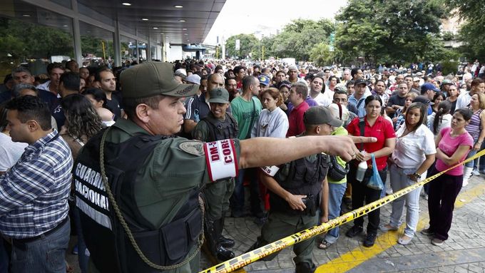 Voják organizuje dav před jedním z obchodů řetězce Daka, který nechal prezident Maduro v zájmu spotřebitelů obsadit armádou.