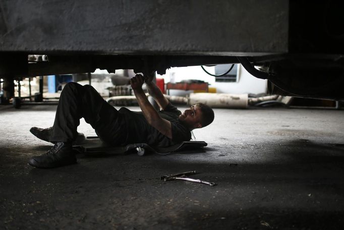 Palestinian Shadi Yassin, 17, works in a car repair garage in Gaza City May 30, 2013. Yassin left school to work as an apprentice in the garage so that he could support his family's income. Apprentice mechanics earn around $100 per month, garage owners said. REUTERS/Mohammed Salem (GAZA - Tags: TRANSPORT SOCIETY EMPLOYMENT) Published: Kvě. 30, 2013, 12:54 odp.