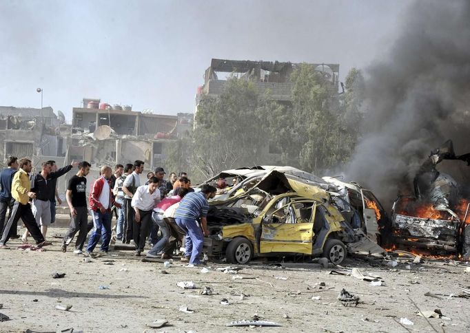 People and security personnel try to remove a car from an explosion site in Damascus May 10, 2012. Dozens of people were killed or wounded in two "terrorist explosions" which struck a southern district of the Syrian capital Damascus on Thursday, state television said. REUTERS/Sana/Handout (SYRIA - Tags: CIVIL UNREST POLITICS) FOR EDITORIAL USE ONLY. NOT FOR SALE FOR MARKETING OR ADVERTISING CAMPAIGNS. THIS IMAGE HAS BEEN SUPPLIED BY A THIRD PARTY. IT IS DISTRIBUTED, EXACTLY AS RECEIVED BY REUTERS, AS A SERVICE TO CLIENTS Published: Kvě. 10, 2012, 7:20 dop.