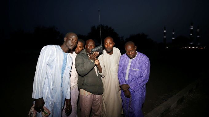 Muži v Maiduguri poslouchají rozhlas krátce po oznámení posunutí voleb.