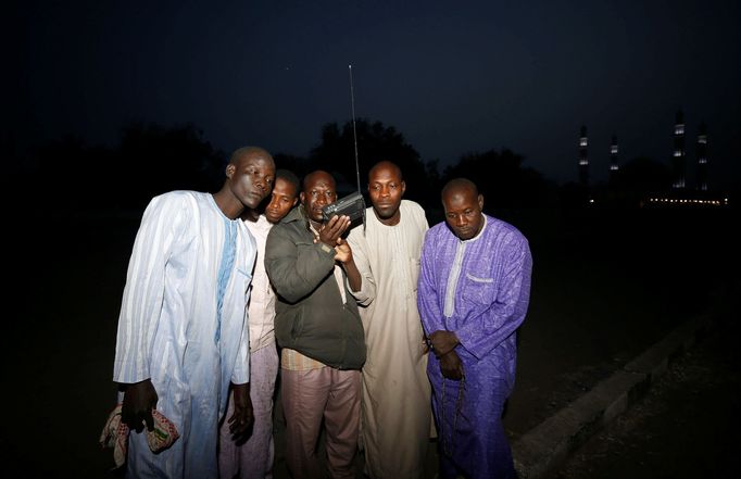 Muži v Maiduguri poslouchají rozhlas krátce po oznámení posunutí voleb.