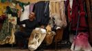 Marco Dilauro gestures next to a mirror with a reflection of his wife Nadia wearing one of his creations, an elaborate costume for the Venice Carnival January 25, 2013. Dilauro, 43, is a tax collector by day, but his real passion is making masks and costumes for the carnival. A resident of Como, northern Italy, he chooses fabrics, ribbons, lace and costume jewellery to make the period costumes after doing extensive research, and wears them at Carnival, which ends on the day before Ash Wednesday. Picture taken January 25, 2013. REUTERS/Alessandro Bianchi (ITALY - Tags: SOCIETY) Published: Led. 27, 2013, 11:29 odp.