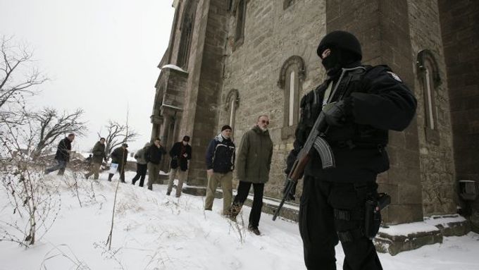 Polský příslušník mezinárodních mírových sil střeží srbský pravoslavný kostel v albánské části Kosovské Mitrovice. V roce 2004 byl skupinou kosovských Albánců zapálen a poničen.