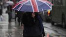 A woman holds an umbrella with a union flag design as she walks in the rain in London in this April 26, 2012 file photo. A quarter of a million rain ponchos, an army of volunteers equipped with umbrellas and rain jackets, and five dedicated weather forecasters - it must be a British Olympics. Planning any outdoor event during the unpredictable British summer, renowned for its potential to throw up more rainy spells than sunshine, requires drawing up contingency plans and keeping a close eye on the weather. REUTERS/Paul Hackett/Files (BRITAIN - Tags: SOCIETY ENVIRONMENT SPORT OLYMPICS) Published: Čer. 27, 2012, 6:49 dop.