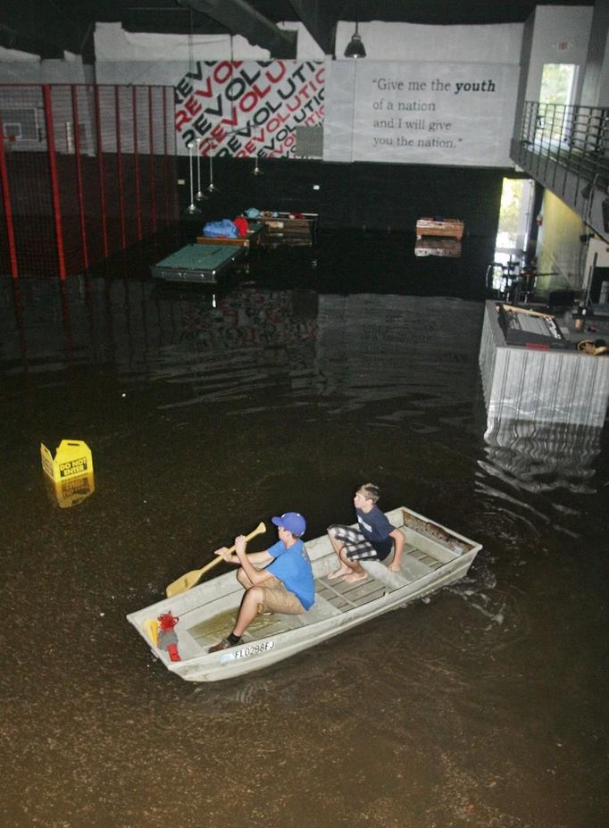 Volunteers Branson Skierski (L) and Carter Chancey, both 14, look for items to salvage as they move their boat through a flooded Melody Christian Academy in Live Oak, Florida, June 27, 2012. Tropical Storm Debby weakened to a tropical depression after it drifted ashore on Florida's Gulf Coast, even as it dumped more rain on flooded areas and sent thousands of people fleeing from rising rivers. REUTERS/Phil Sears (UNITED STATES - Tags: ENVIRONMENT DISASTER) Published: Čer. 28, 2012, 2:46 dop.