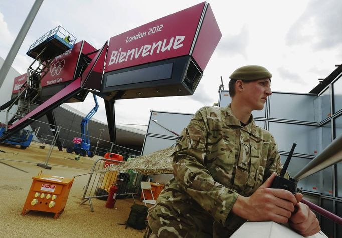 A soldier looks out from a vantage point near an entrance to the London 2012 Olympic Park at Stratford in London July 12, 2012. Britain could be forced to deploy thousands of extra troops in London during the Olympics after a last-minute security blunder dealt an embarrassing blow to the government just two weeks before the Games. REUTERS/Luke MacGregor (BRITAIN - Tags: SPORT OLYMPICS MILITARY) Published: Čec. 12, 2012, 4:52 odp.