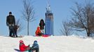 Children ride down a hill on a toboggan as One World Trade Center is seen in Jersey City, New Jersey, February 9, 2013. A blizzard packing hurricane-force winds pummelled the northeastern United States on Saturday, killing at least one person, leaving about 600,000 customers without power and disrupting thousands of flights. REUTERS/Eduardo Munoz (UNITED STATES - Tags: ENVIRONMENT DISASTER) Published: Úno. 10, 2013, 12:49 dop.