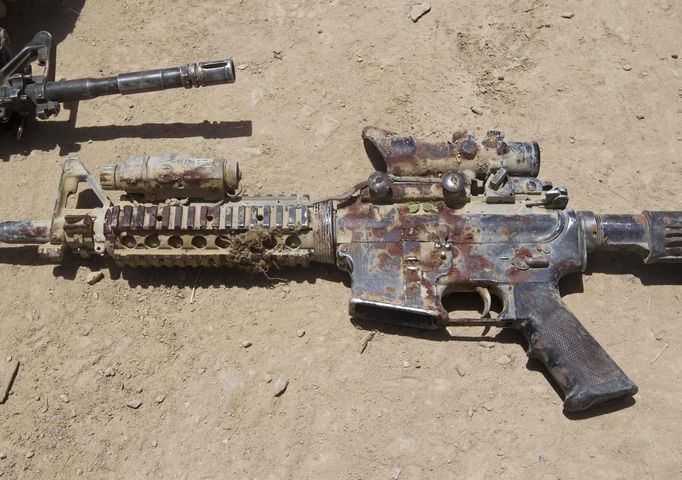 A blood-covered M4 rifle belonging to Sgt. Matt Krumwiede, who was wounded by an improvised explosive device (IED), lies on the ground in southern Afghanistan in this June 12, 2012 file photo. On June 12, 2012, Krumwiede was on patrol in Afghanistan when he stepped on an IED, which tore away both his legs, damaged his left arm, and ripped open his abdominal cavity. The 22-year-old has since undergone around 40 surgeries and is learning to walk with prosthetic legs. He is keen to re-join the infantry as soon as his injuries allow. U.S. troops have been in Afghanistan since 2001. Thousands of Afghan elders gathered in Kabul on November 21, 2013 at a Loya Jirga, or grand council, to debate a crucial security pact with the United States, a day after Kabul and Washington reached a draft agreement laying out the terms under which U.S. troops may stay beyond 2014. Picture taken June 12, 2012. REUTERS/Shamil Zhumatov/Files (AFGHANISTAN - Tags: MILITARY HEALTH SOCIETY POLITICS CIVIL UNREST) ATTENTION EDITORS: PICTURE 06 OF 33 FOR PACKAGE 'AFTER AFGHANISTAN - LEARNING TO WALK AGAIN' TO FIND ALL IMAGES SEARCH 'MATT KRUMWIEDE'