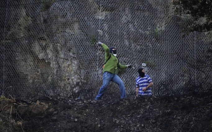 Two miners throw stones during confrontations with the riot Civil Guard after setting an incendiary device to a barricade near highway A-66 in Vega del Rey, June 4, 2012. Spain's economy contracted for the second time since late 2009 and four years of stagnation and recession have pushed unemployment above 24 percent, the highest rate in the European. REUTERS/Eloy Alonso (SPAIN - Tags: POLITICS CIVIL UNREST BUSINESS EMPLOYMENT) Published: Čer. 4, 2012, 11:22 dop.