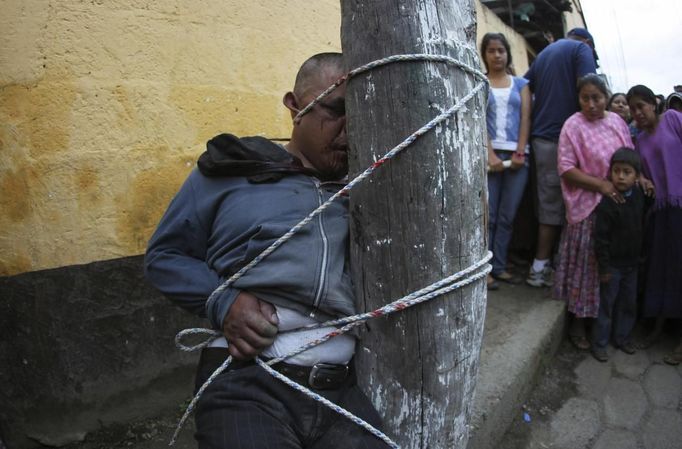 A man, who was accused of theft, is tied up and beaten by villagers of Tactic, in Alta Verapaz region, about 189km (117 miles) from Guatemala City, September 13, 2012. The local community tied up and beat four men who were accused of theft in the aftermath of a school killing, which had occurred on Wednesday. The man, who had entered a classroom and killed two children, ages 8 and 13, with a machete, was lynched and burnt alive by a mob, local media reported. REUTERS/Jorge Dan Lopez (GUATEMALA - Tags: CRIME LAW SOCIETY) Published: Zář. 13, 2012, 6:08 odp.